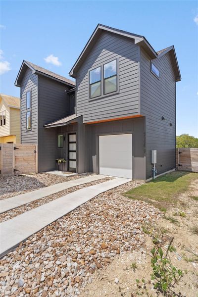 A modern two-story home with dark gray siding, a contemporary front door, and an attached garage. A modern two-story home with dark gray siding, a contemporary front door, and an attached garage.
