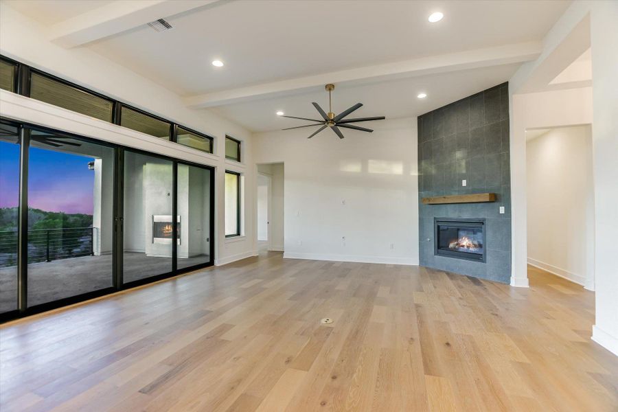Living room with a fireplace, a ceiling fan, light wood-style flooring, beamed ceiling, and recessed lighting