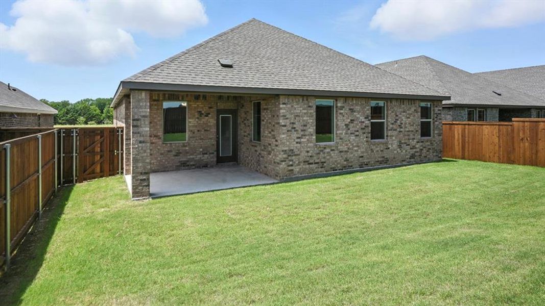 Rear view of property featuring brick siding, a fenced backyard, roof with shingles, and a patio area Rear view of property featuring brick siding, a fenced backyard, roof with shingles, and a patio area
