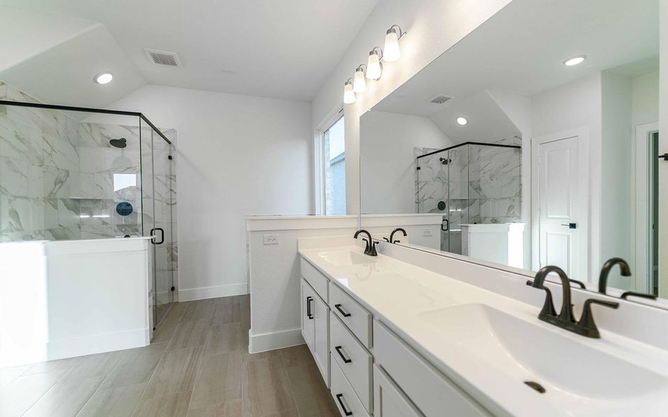 Bathroom featuring lofted ceiling, a marble finish shower, double vanity, and recessed lighting