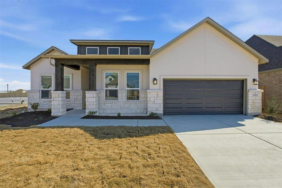 Contemporary stucco and stone exterior featuring a dark gray garage door, covered entry with dark wood-finish beams, and multiple windows