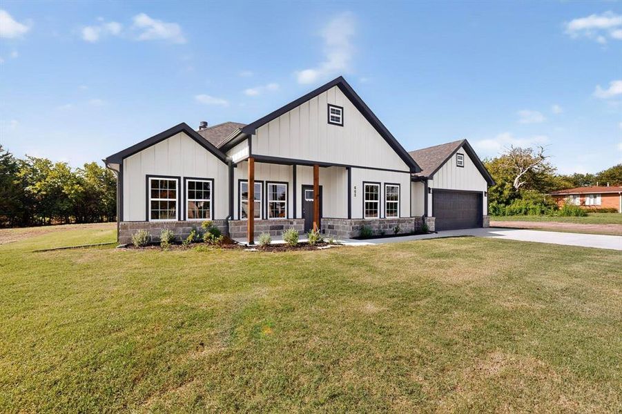 Modern inspired farmhouse with a porch, a front lawn, driveway, board and batten siding, and stone siding Modern inspired farmhouse with a porch, a front lawn, driveway, board and batten siding, and stone siding