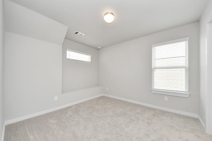 Secondary bedroom features plush carpeting, large windows that let in plenty of natural light, bright paint, and spacious closets. Sample photo of completed home with similar floor plan. Actual colors and selections may vary.