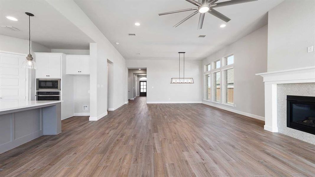 Unfurnished living room with ceiling fan, wood-type flooring, and a tile fireplace