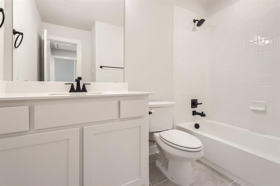 Full bathroom with vanity, tiled shower / bath combo, toilet, and tile patterned floors