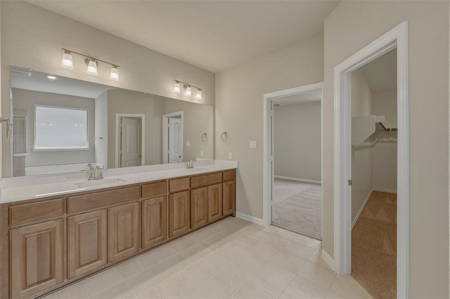 Double vanity with light wood-finish cabinetry, white countertops, and dual undermount sinks Double vanity with light wood-finish cabinetry, white countertops, and dual undermount sinks