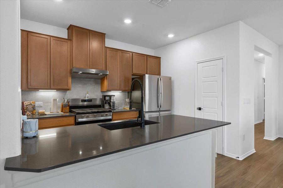 A well-appointed kitchen features rich wood-look cabinetry, gleaming stainless steel appliances, and sleek dark countertops.