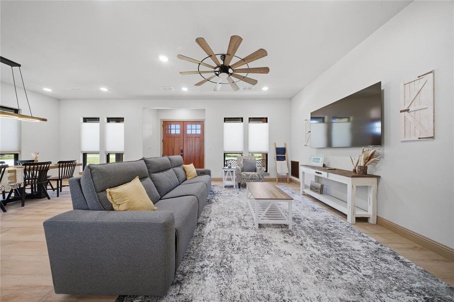 Spacious living area featuring light wood-finish flooring and recessed lighting
