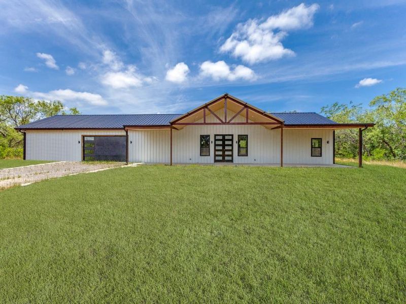 View of front of house featuring driveway, a front yard, metal roof, and french doors