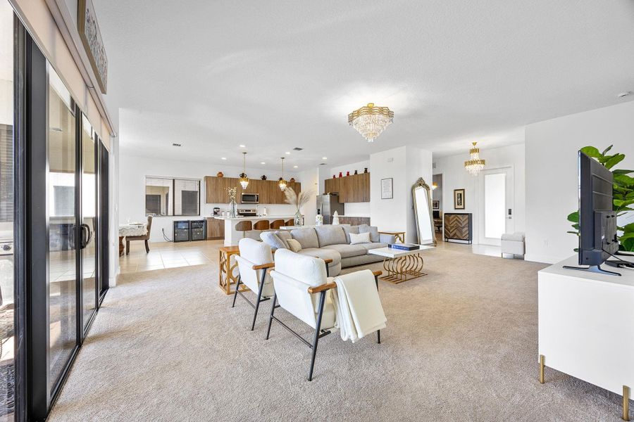 Living room with a chandelier, light colored carpet, and recessed lighting