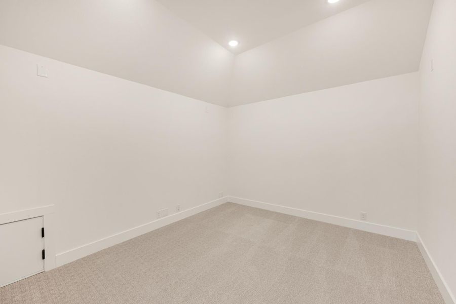 Empty room with white walls, gray carpet, recessed lighting, and a built-in cabinet door