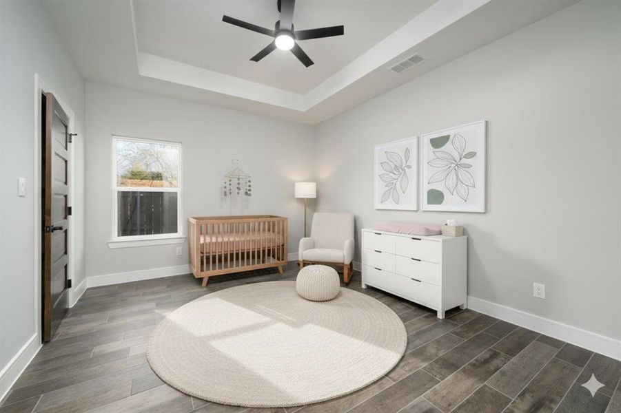 Virtually generated decoration Bedroom featuring a nursery area, a tray ceiling, wood finish floors, and ceiling fan