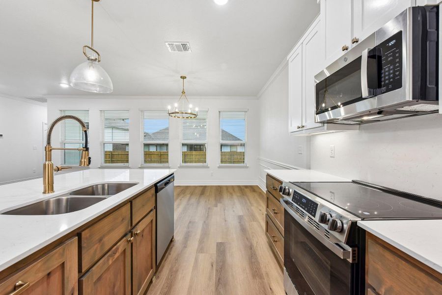 A well-appointed kitchen features a large island with dual sinks, modern appliances, and seamless flow into a bright dining area. A well-appointed kitchen features a large island with dual sinks, modern appliances, and seamless flow into a bright dining area.