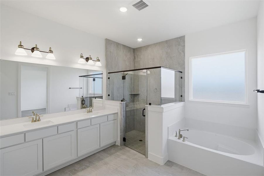 Bathroom featuring double vanity, a stall shower, a garden tub, and recessed lighting