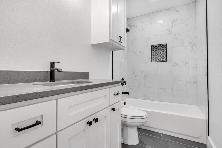 Full bathroom featuring tiled shower / bath combo, tile flooring, toilet, and vanity