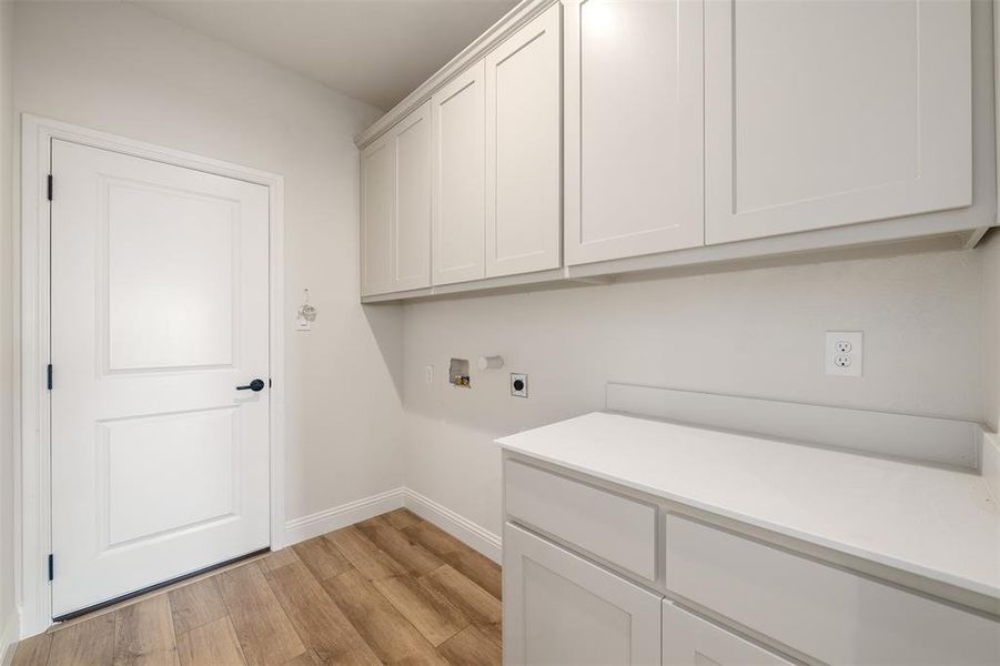 Laundry area featuring cabinet space, washer hookup, hookup for an electric dryer, and light wood-style flooring