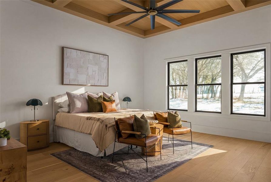 Bedroom featuring light wood-finish flooring, a coffered ceiling with a dark-bladed ceiling fan, and three vertical windows with black framing