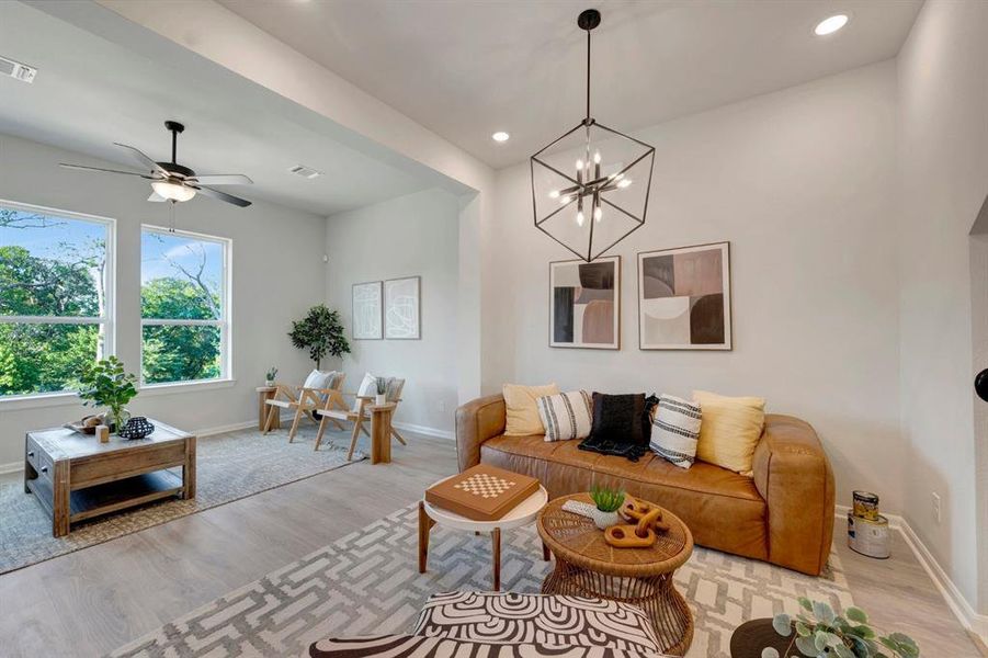 Bright living area featuring light wood-finish flooring, recessed lighting, and large windows
