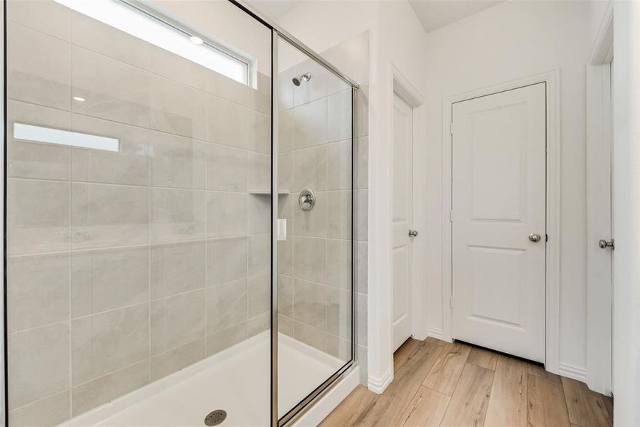 Bathroom with hardwood / wood-style flooring and a shower with shower door