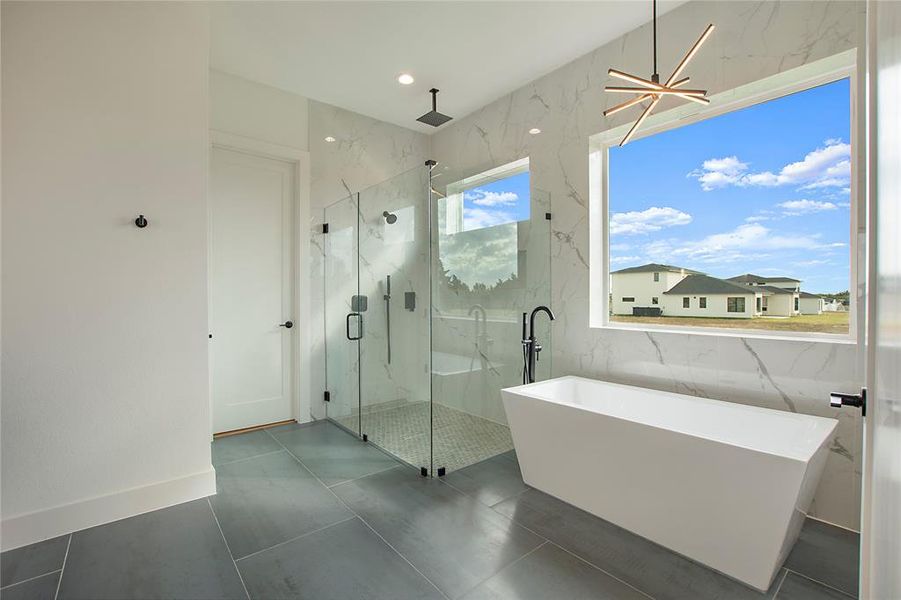 Bathroom featuring tile patterned flooring, a notable chandelier, and shower with separate bathtub