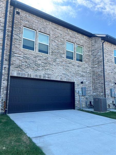 View of side of home featuring an attached garage, concrete driveway, and brick siding