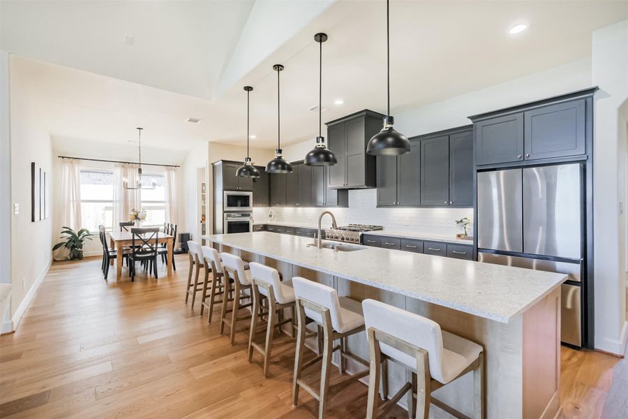Open-concept kitchen and dining view with dark cabinets, light island, and stainless steel appliances.