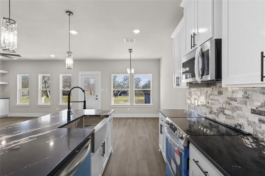 Kitchen featuring white cabinetry, hanging light fixtures, tasteful backsplash, and appliances with stainless steel finishes