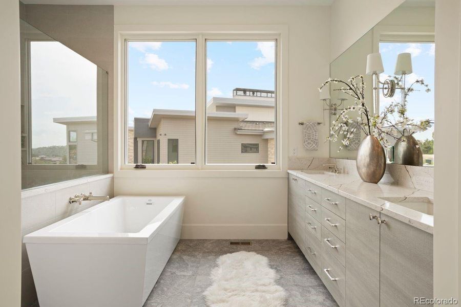 Primary bath with elegant dual-sink vanity with sleek cabinetry, quartz countertops, and a full-width mirror accented by contemporary sconces.