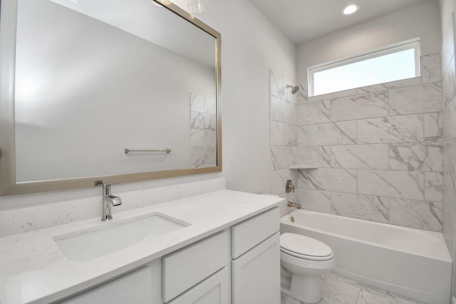 Secondary bath features tile flooring, bath/shower combo with tile surround, light stained wood cabinets, beautiful light countertop. Sample photo of completed home with similar floor plan. Actual colors and selections may vary. Secondary bath features tile flooring, bath/shower combo with tile surround, light stained wood cabinets, beautiful light countertop. Sample photo of completed home with similar floor plan. Actual colors and selections may vary.