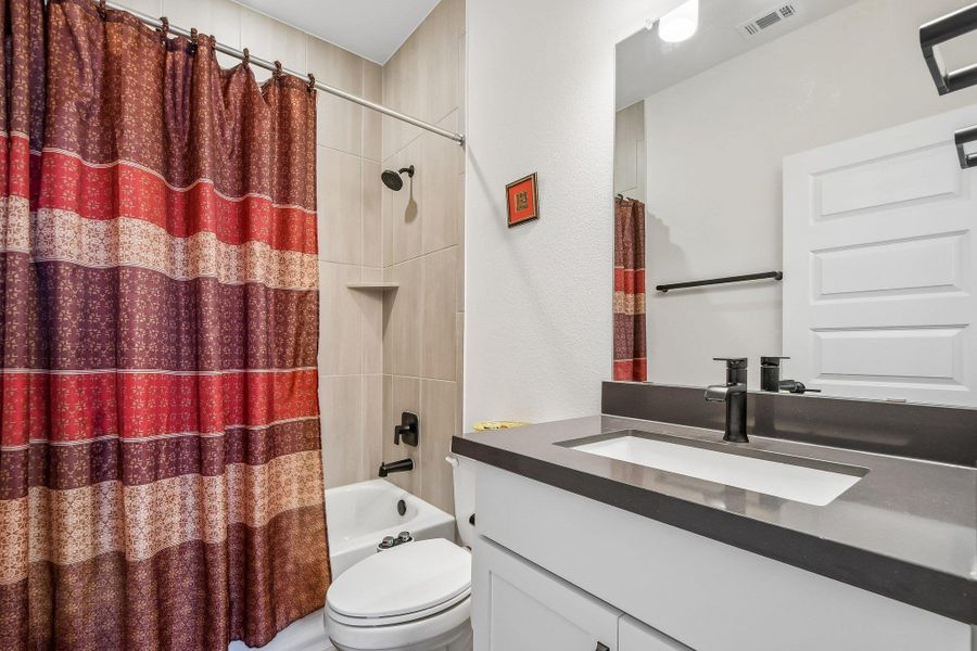 Modern bath features a single vanity, clean lines, and a classic shower-over-tub design.