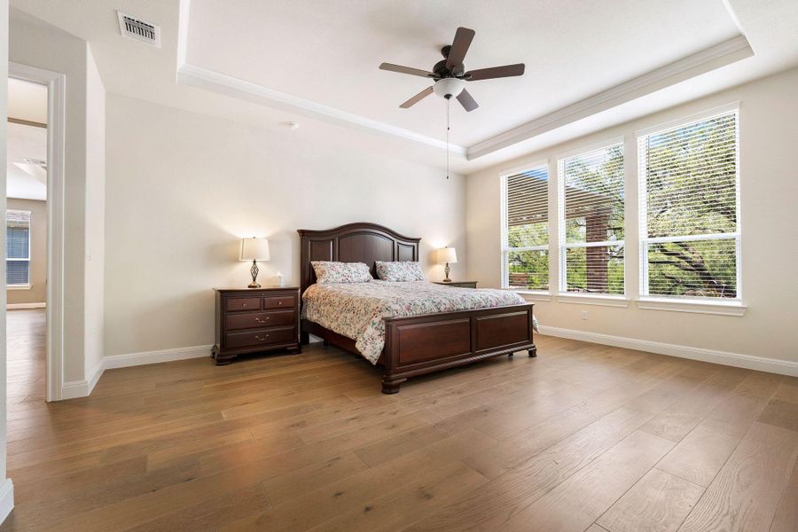 Sun-filled primary bedroom with a spacious layout and beautiful wood flooring. Sun-filled primary bedroom with a spacious layout and beautiful wood flooring.