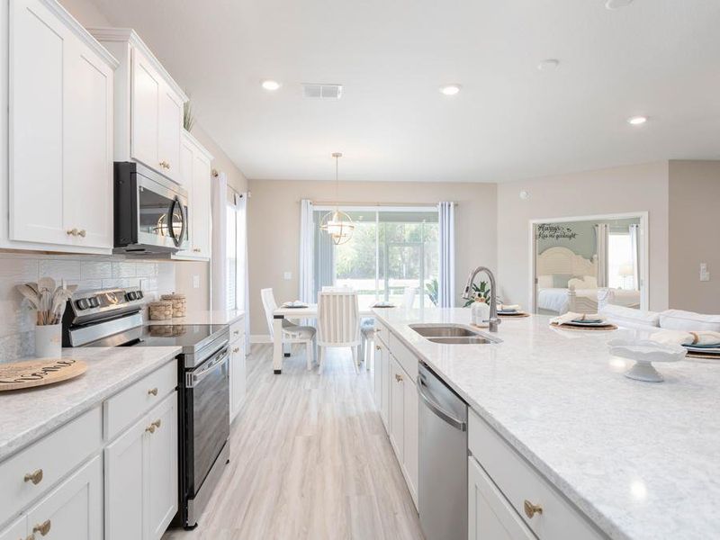 Open kitchen with counter-height island and stainless steel appliances - Shelby home plan by Highland Homes