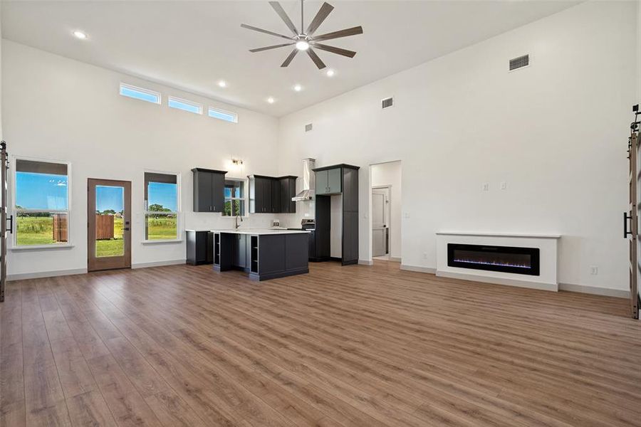 Open-concept living space featuring wood-finish flooring, a contemporary ceiling fan, and recessed lighting