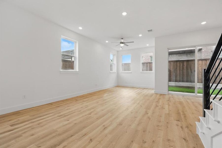 Unfurnished living room featuring stairs, a ceiling fan, recessed lighting, light wood-style flooring, and baseboards