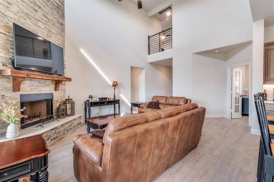Living area with a fireplace, light wood-style floors, and a high ceiling Living area with a fireplace, light wood-style floors, and a high ceiling