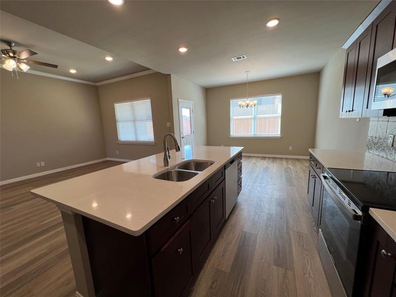 Kitchen with stainless steel appliances, a center island with sink, a healthy amount of sunlight, and sink