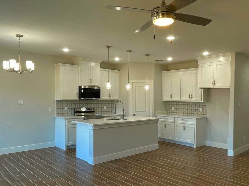 Kitchen featuring white cabinetry, stainless steel appliances, and a center island with sink