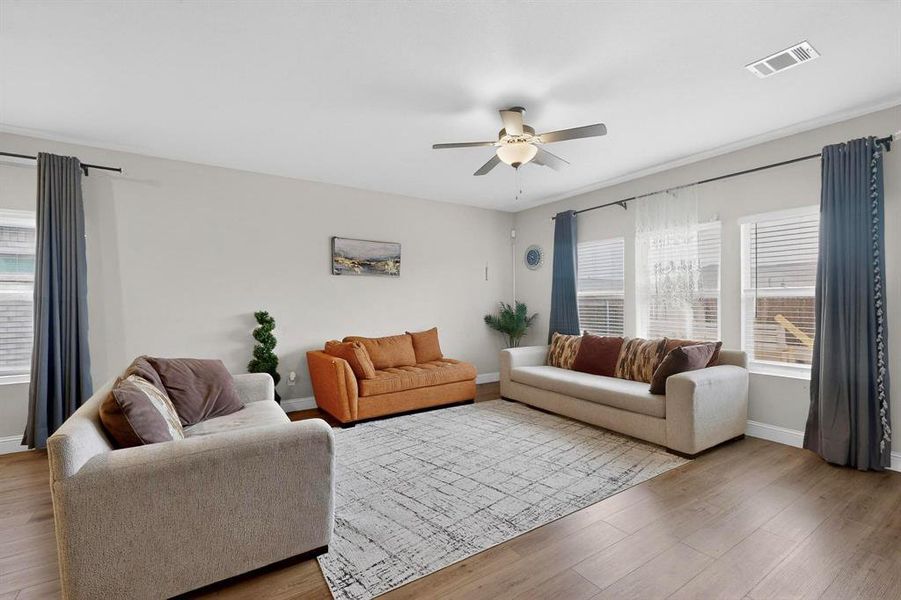 Living area with healthy amount of natural light, a ceiling fan, and wood finished floors Living area with healthy amount of natural light, a ceiling fan, and wood finished floors
