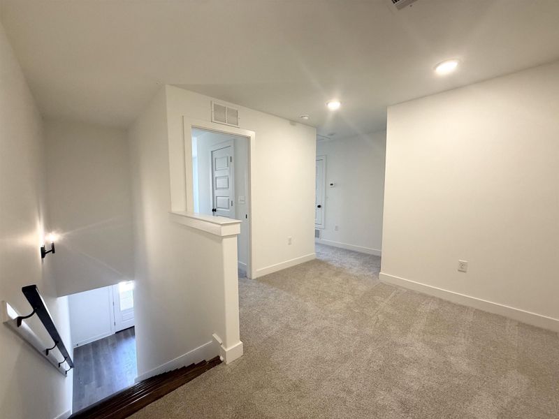 Hallway featuring an upstairs landing, dark carpet, and recessed lighting