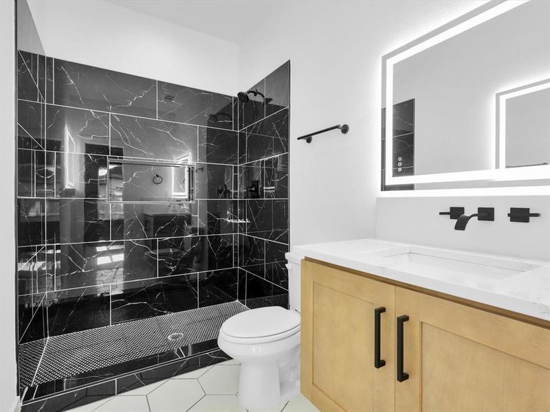 Bathroom with vanity, tiled shower, tile patterned flooring, and toilet