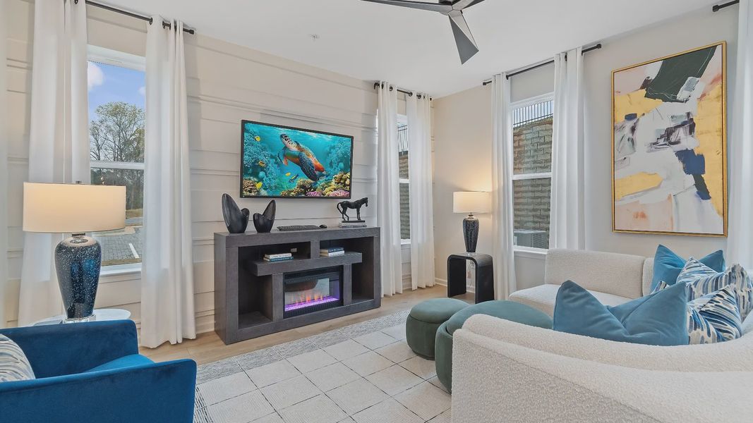Spacious family room with large windows, ceiling fan and open layout in new construction townhome at Auburn Ridge.
