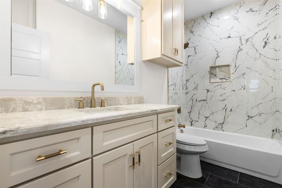 Full bathroom featuring tiled shower / bath, tile patterned flooring, vanity, and toilet