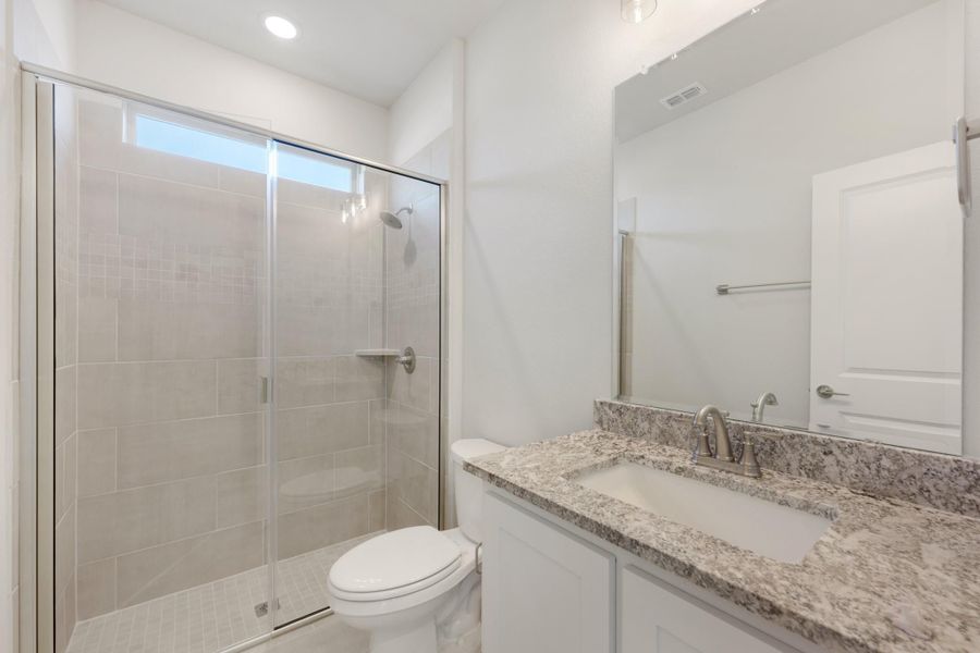 Bathroom with glass-enclosed tile shower, granite countertop vanity, and white cabinets Bathroom with glass-enclosed tile shower, granite countertop vanity, and white cabinets