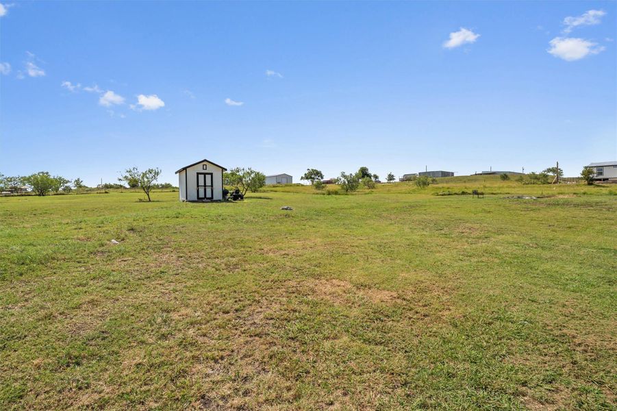 View of grassy yard featuring a storage unit and a view of rural / pastoral area