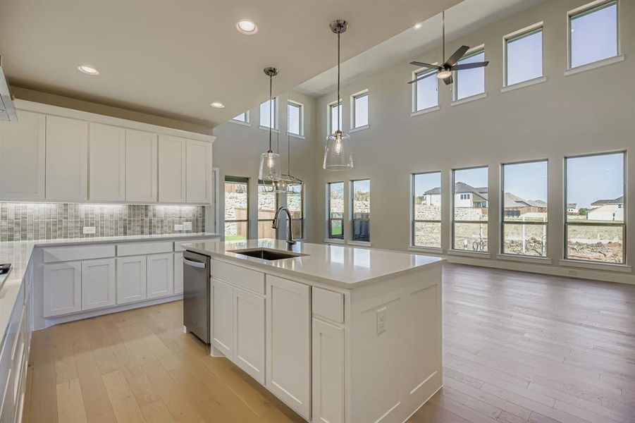 Kitchen with white cabinets, backsplash, recessed lighting, a kitchen island with sink, and hanging light fixtures