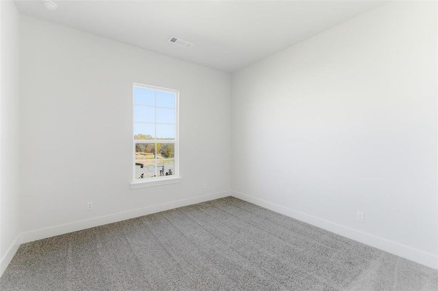 Empty room with light colored carpet and baseboards