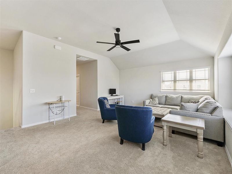 Living room with ceiling fan, lofted ceiling, and light colored carpet