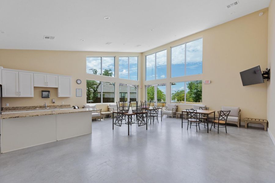A spacious community room features a kitchen area with granite counters and numerous tall windows. A spacious community room features a kitchen area with granite counters and numerous tall windows.