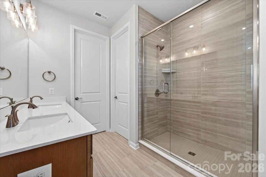 Dual vanity primary bathroom with walk-in tiled shower