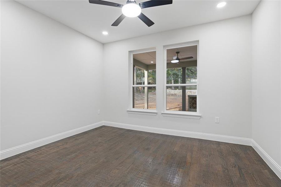 Bright interior space featuring two large windows, wood-finish flooring, recessed lighting, a ceiling fan, and white baseboards Bright interior space featuring two large windows, wood-finish flooring, recessed lighting, a ceiling fan, and white baseboards
